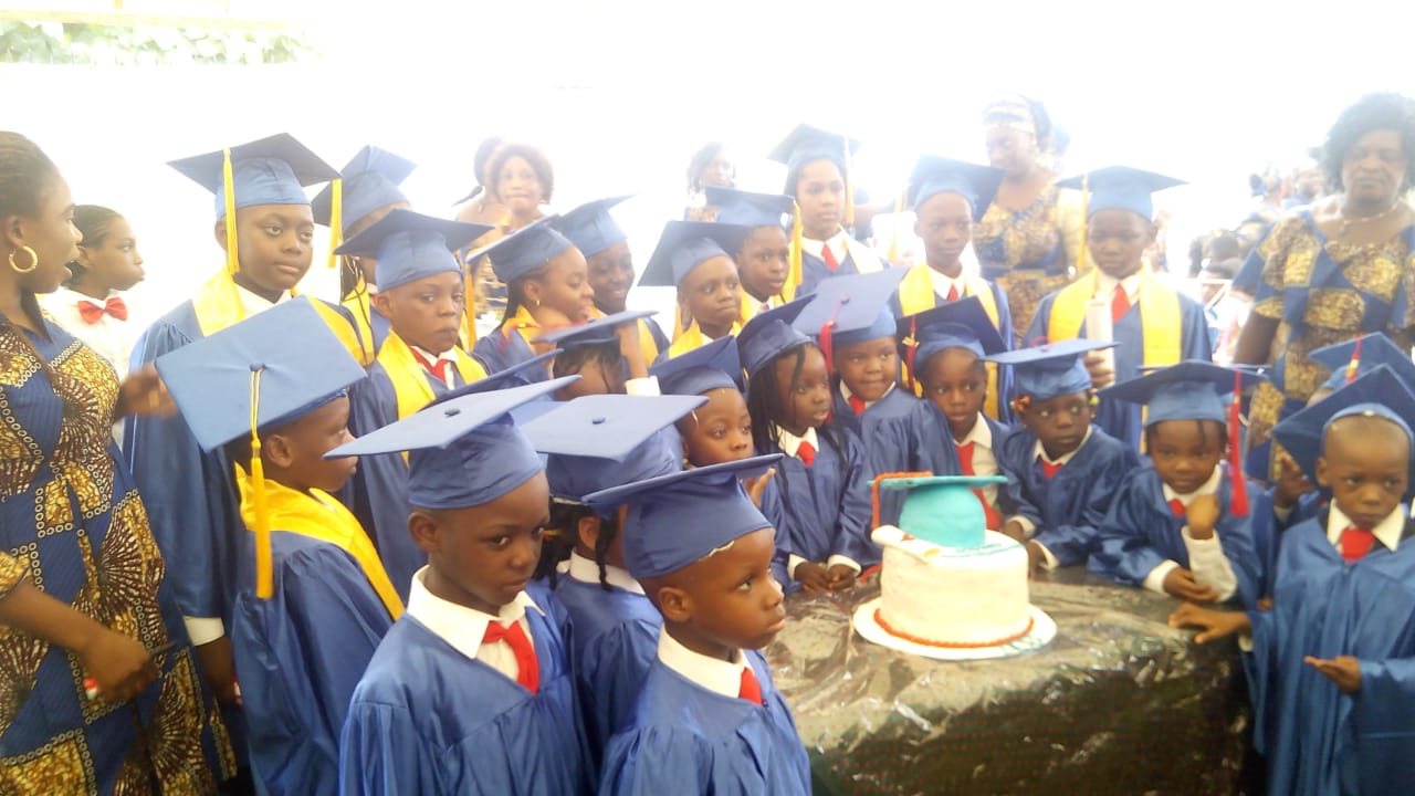 Graduating class of 2017 in caps and gowns around a cake